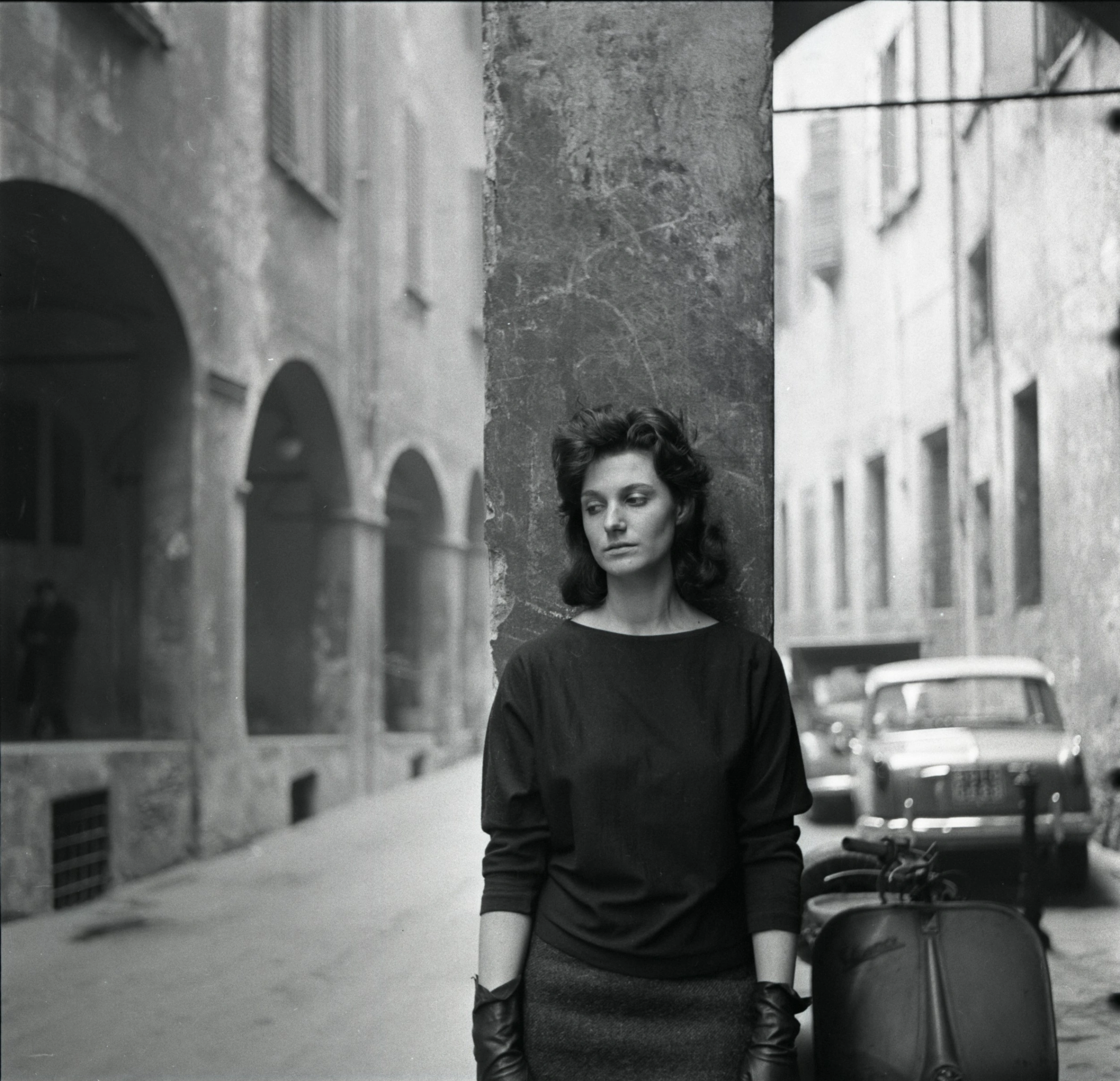 Una giovane donna con sguardo malinconico, appoggiata a un portico del centro storico di Bologna. Foto di Antonio Masotti © Cineteca